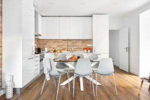 a kitchen with white cabinets and a table and chairs at JOIVY Bright and Beautiful 4BR Apt 5 mins to Rato subway in Lisbon