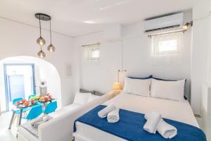 a white bedroom with a bed and a blue blanket at Anemona Apartment Tinos in Kalloni Tinou