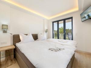 a bedroom with a large white bed with a window at Haus Avella Wohnung Nr. 29 in Binz