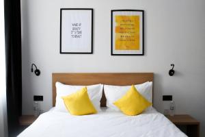 a bed with two yellow pillows and three pictures on the wall at Number 21 by DBI in Kyiv