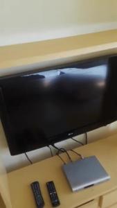 un monitor de ordenador en un escritorio con dos mandos a distancia en Dre Broeders Apartments Juan Dolio, en Juan Dolio