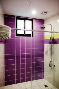 Baño de azulejos púrpura con ducha de cristal en Hualien KeyInn Space, en Hualien City