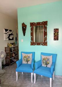 2 sillas azules en la sala de estar con espejo en Apartamento Aconchego da vovó, en Peruíbe