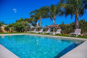 a swimming pool with lounge chairs and palm trees at Residence I Faraglioni in Scopello