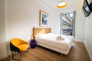 a bedroom with a bed and a chair and a window at Central Roomss in San Sebastián
