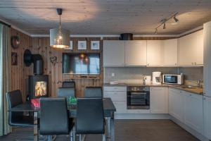 a kitchen with a table and chairs and a kitchen with white cabinets at Mountain Lodge, ToppTrysil 6+1 guest -Skihytta in Trysil