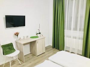 Habitación con escritorio, TV y cortinas verdes. en Vila Nona Apartment, en Sibiu