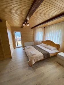 una camera da letto con un grande letto in una camera in legno di Котедж Mountain house a Jaremče