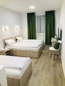 two beds in a room with green curtains and a desk at Vila Nona Apartment in Sibiu