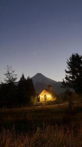 Una casa iluminada en un campo por la noche en Hotel Salto del Carileufu, en Pucón