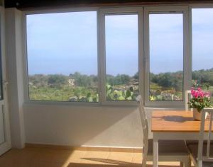 a dining room with a table and three windows at Kefalas nr Almyrida sea view cottage in Chania Town