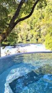 een zwembad van blauw water naast een rivier bij Hotel Salto del Carileufu in Pucón