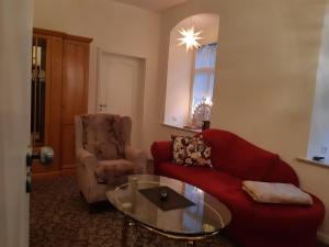 a living room with a red couch and a glass table at K5-Suites in der Altstadt Annaberg-Buchholz in Annaberg-Buchholz