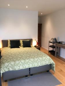 a bedroom with a large bed and a desk at B&B Den Biesthoek in Grimbergen