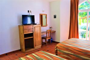- une chambre avec un lit et un bureau avec une télévision dans l'établissement Hotel Mexico Lindo, à Santa Cruz Huatulco
