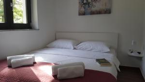 a bedroom with a large white bed with two chairs at Apartments ARTEMIS in Baška