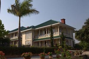 a large house with a palm tree in front of it at Pine Hill Resort in Kalaw