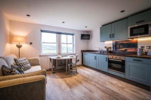 a kitchen with blue cabinets and a couch and a table at Stones Throw in Grayrigg