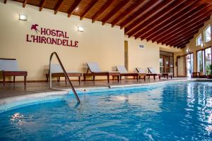 a swimming pool at a hotel with chairs and a sign at Hostal L' Hirondelle in La Falda