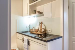 a kitchen with white cabinets and a sink at Key West 5 in Wangerooge +11 photos