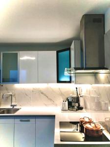 cocina con armarios blancos, fregadero y fogones en Fabulous Lakeside Family Apartment | 4 Rooms en Montreux