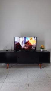 a flat screen tv sitting on a black entertainment center at Lindo Apartamento Varanda no centro de Paulo Afonso in Paulo Afonso