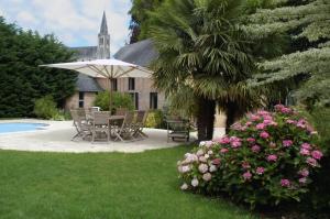 une terrasse avec des chaises et une table avec un parasol dans l'établissement La Demeure de l'Ile, à Craon