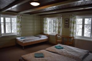 1 dormitorio con 2 camas, mesa y ventanas en Chata Stará Brusírna, en Bedřichov