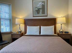 um quarto com uma cama com 2 candeeiros e uma cadeira em Oasis Guest House em Boston