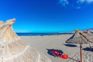 - une plage avec des parasols en paille et l'océan dans l'établissement Sunny Cozy Nice Apartment LosCristianos WiFi,Pool, à Los Cristianos