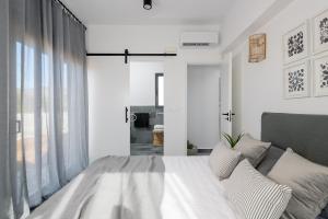 a white bedroom with a bed and a window at Seawater Villa in Lakhania