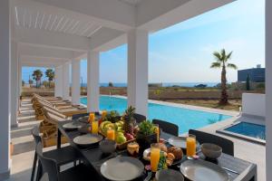 a dining room with a table with food and a pool at Seawater Villa in Lachania