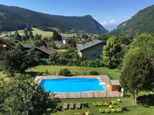 a swimming pool in a field with a house and mountains at Le Chamechaude Bed&Breakfast in Le Sappey-en-Chartreuse