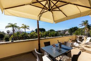 eine Terrasse mit einem Sonnenschirm, einem Tisch und Stühlen in der Unterkunft Villa Agave in Capo Vaticano