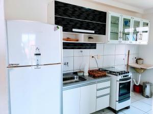 a white kitchen with a refrigerator and a sink at Apartamento Modus Vivendi in Ilhéus