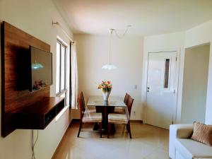 a dining room with a table with a vase of flowers on it at Apartamento Modus Vivendi in Ilhéus