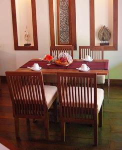 einen Holztisch mit 2 Stühlen und einen Tisch mit einer Schüssel in der Unterkunft Villa Korbhun Khinbua in Chiang Mai