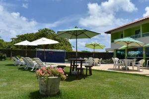 a patio with tables and chairs and umbrellas at Pousada Solar Dos Carneiros in Tamandaré