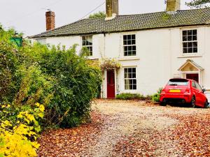 a red car parked in front of a white house at Cosy Cottage in Durham City in Durham