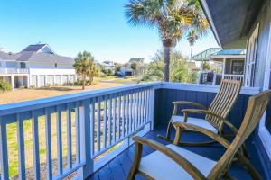 two chairs on a porch with a palm tree at Beachside Cottage in Isle of Palms