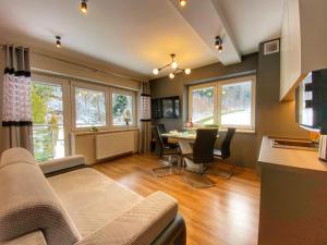salon ze stołem, krzesłami i oknami w obiekcie Kurort Kozubnik Apartament 33 Wellness &SPA w mieście Porąbka
