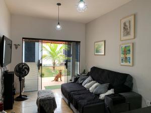 ein Wohnzimmer mit einem schwarzen Sofa und einem Hund in der Unterkunft Hostel Suite Home in Saquarema
