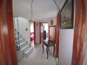 un corridoio con scala e tavolo in una casa di Hospedaje Los Cedros- Monguí a Monguí