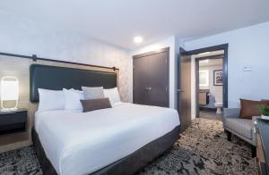 um quarto com uma grande cama branca e uma cadeira em The Crystal Lodge em Whistler