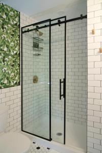 a glass shower in a bathroom with white tiles at The Juniper Inn in St. Catharines
