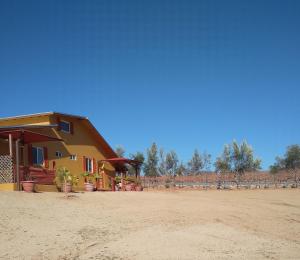 a house on the beach next to a dirt field at Posada Soleil Bed & Breakfast in Valle de Guadalupe