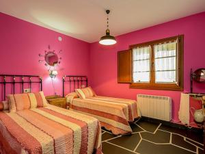 1 dormitorio con 2 camas y paredes rosas en Belvilla by OYO Casa de campo Villanueva de Oscos en Villanueva de Oscos