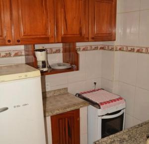 a kitchen with wooden cabinets and a white stove top oven at Flats Paraty in Paraty