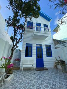 a white house with blue windows and a blue door at Cát Homestay in Quy Nhon