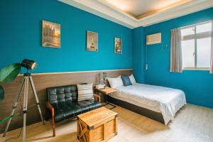 een slaapkamer met blauwe muren en een bed en een stoel bij Fun Trip - Fu May Sea View Holiday house l 無敵海景交誼廳 l 附汽機車租賃 l in Taitung